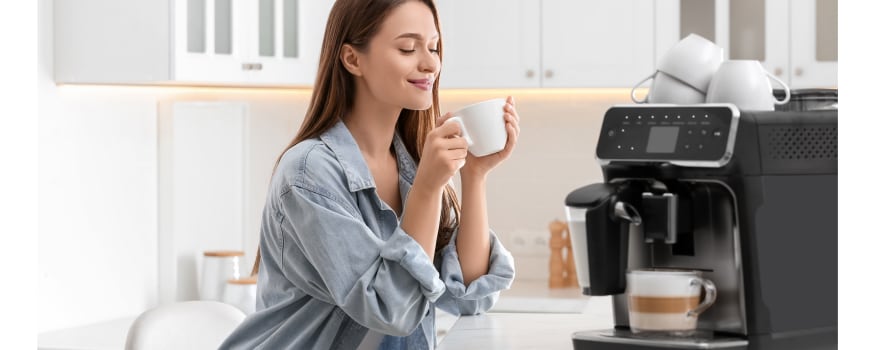 A woman smiling as she sips freshly brewed coffee