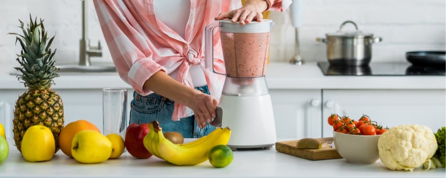 A woman using a blender to blend fruit